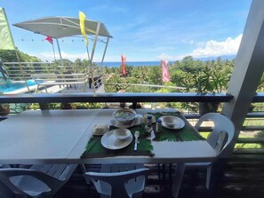 A dining table set outdoors with a view of the ocean and palm trees. - overlooking view house samal Island with mini pool (Island Garden City of Samal)