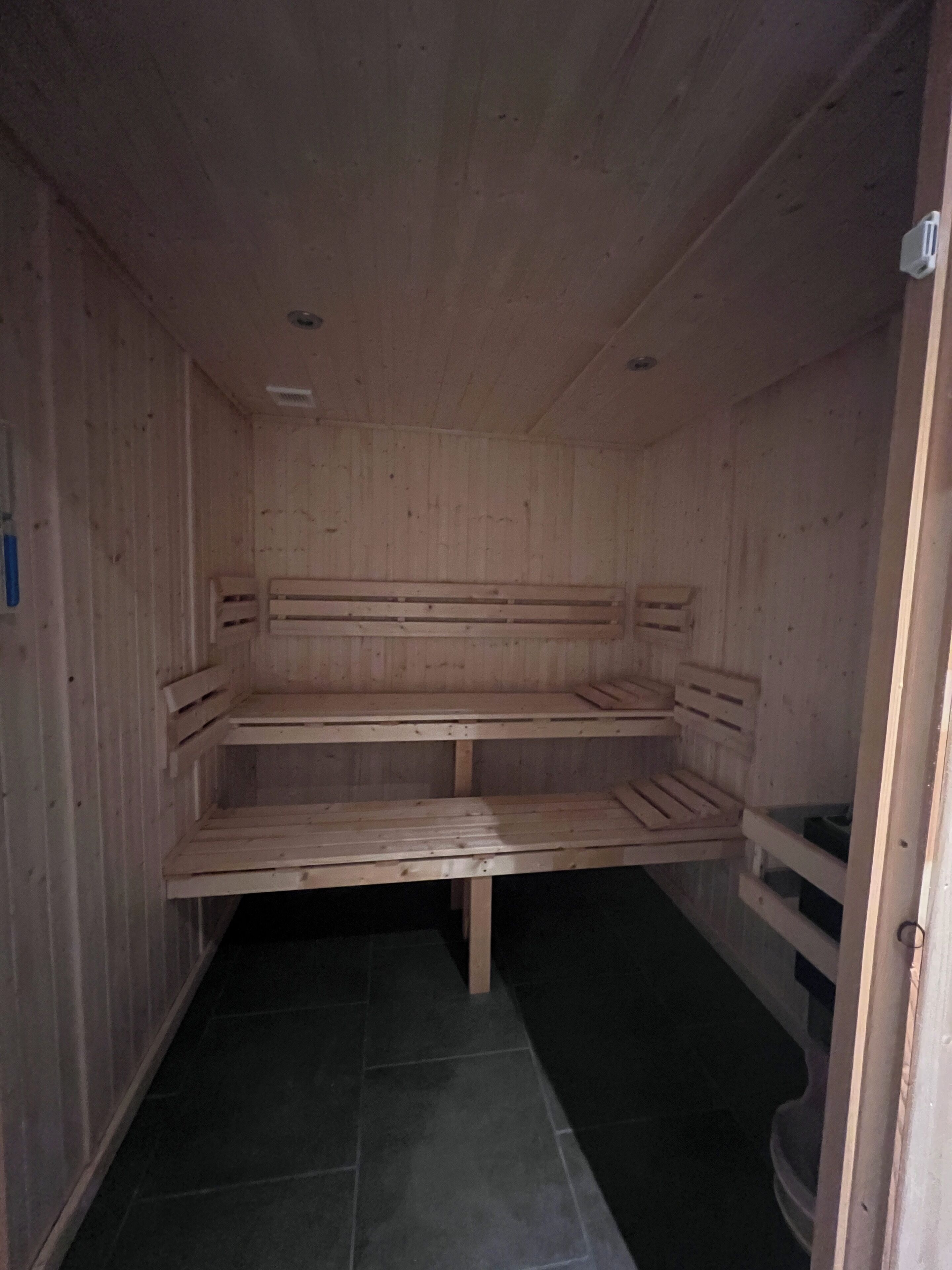 Un sauna avec des bancs en bois et un sol carrelé.