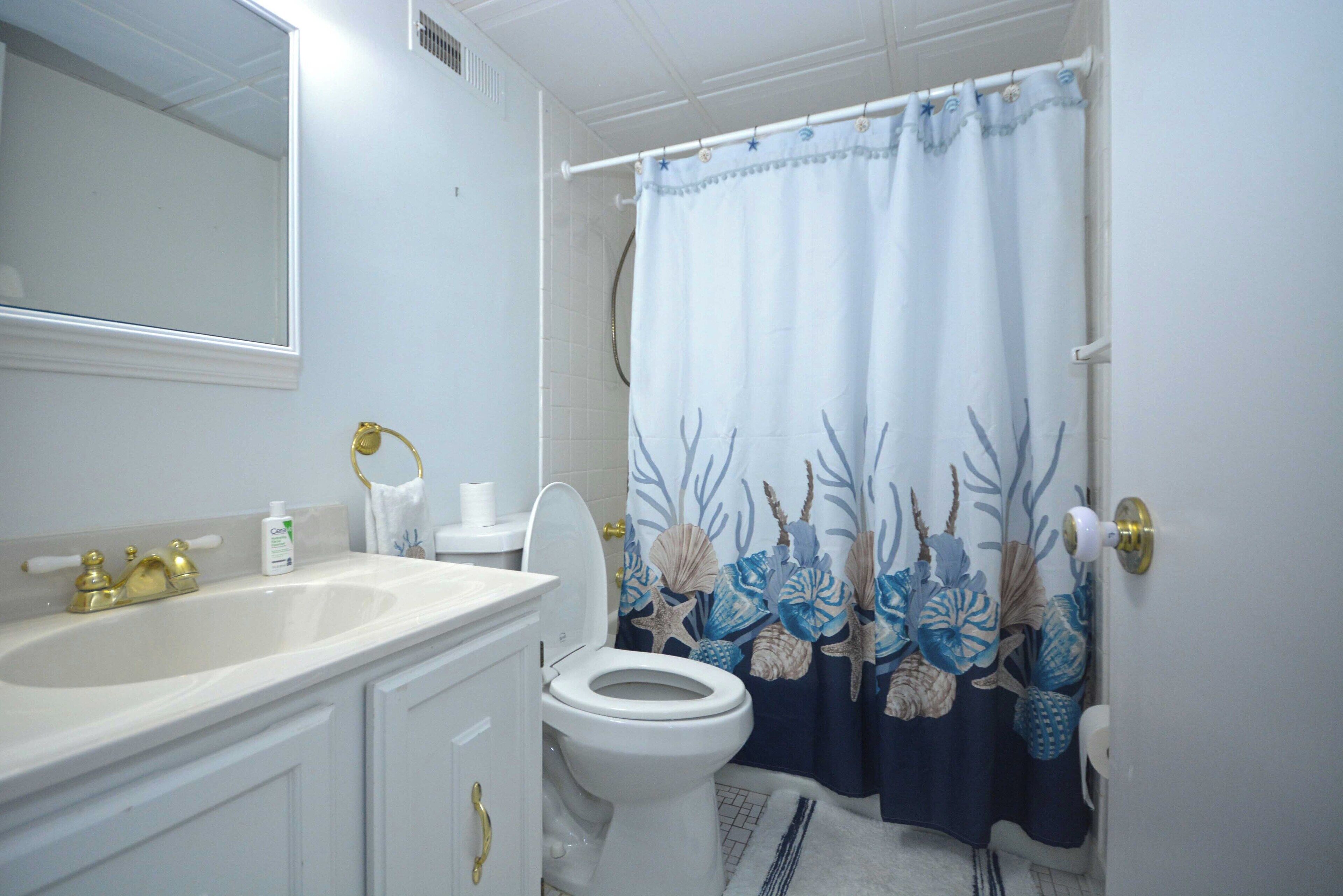 Un bagno con un lavandino bianco, un water e una tenda della doccia con decorazioni a tema marino.