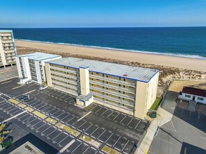 Un hotel de varios pisos con un estacionamiento frente a él, con vistas a una playa.