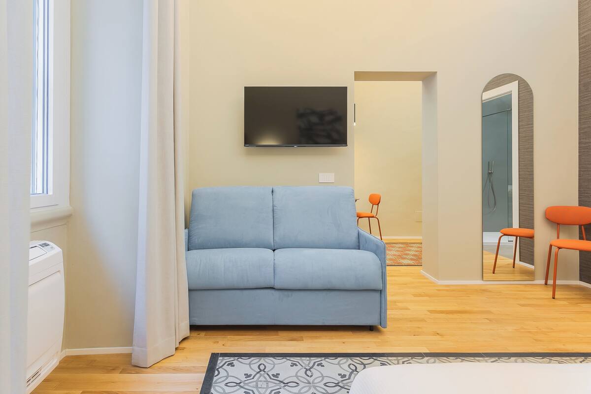 Una sala de estar moderna con un sofá azul claro, un televisor de pantalla plana montado en la pared y piso de madera.