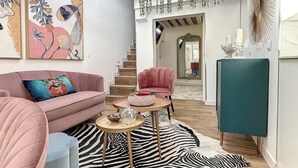 Een moderne woonkamer met een roze bank, een vloerkleed met zebraprint en een trap naar een hoger niveau.