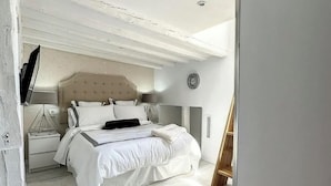 Een slaapkamer met een bed, nachtkastje, lamp en een klok aan de muur.