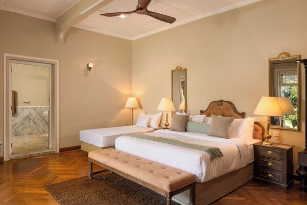A double bed with a bench, two bedside tables with lamps, a ceiling fan, and a large mirror on the wall.