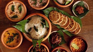 A variety of dishes served on clay plates with banana leaves, including rice, curries, and flatbreads.