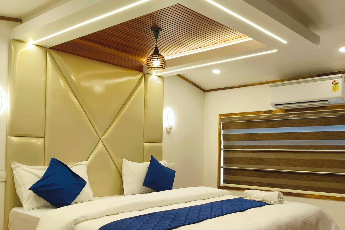 A modern bedroom with a bed, headboard, and ceiling lights.