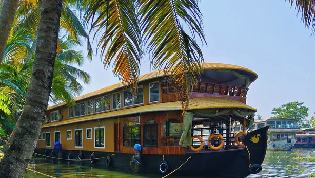 A houseboat with multiple decks, a covered upper deck, and a large open deck area. - Vinayak House Boats (Alleppey)