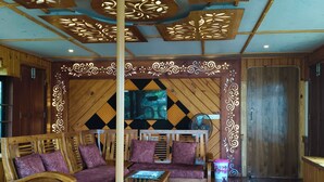 A wooden interior with a sofa, a table, and a decorative ceiling. - Vinayak House Boats (Alleppey)