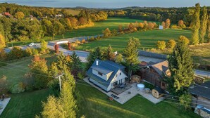 A modern house with a large yard, a driveway, and a road nearby.