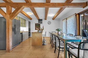 A kitchen with wooden beams, a central island, and a dining area with chairs. - Villa in Dolni Branna With Sauna (Dolni Branna)