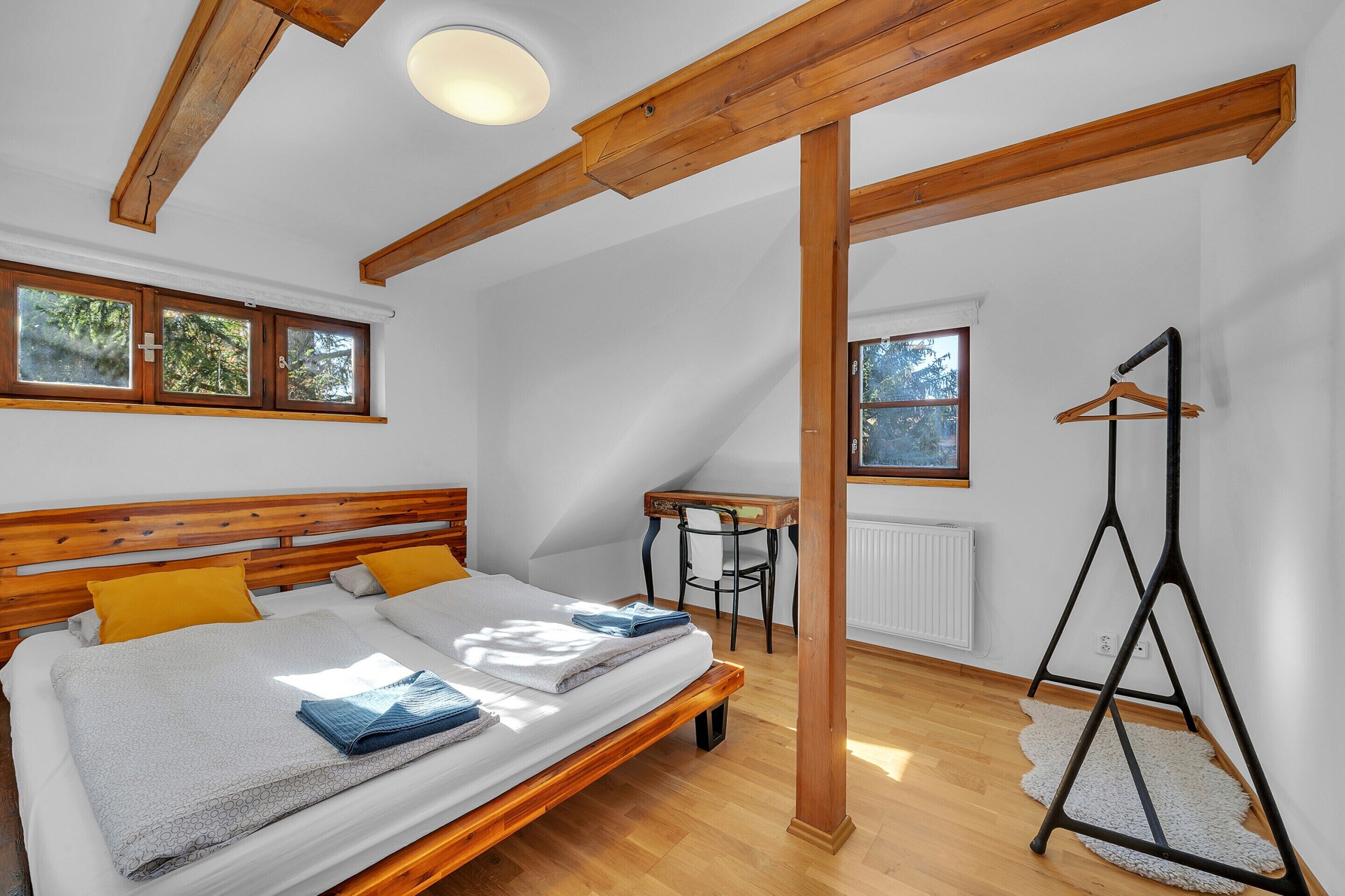Un dormitorio con una cama de madera, una mesita pequeña y una silla.