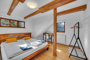 A bedroom with a wooden bed, a small table, and a chair. - Villa in Dolni Branna With Sauna (Dolni Branna)