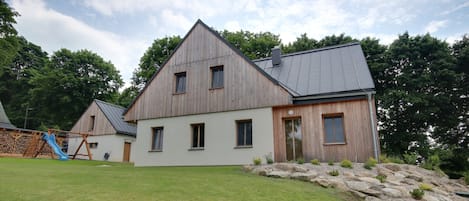 A large, single-story house with a sloped roof, a wooden exterior, and a well-maintained lawn.