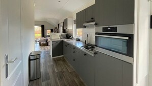 A modern kitchen with grey cabinetry, a built-in oven, and a stainless steel range hood. - Farmhouse-style Chalet in Sint Nicolaasga (Sint Nicolaasga)