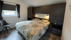 A bedroom with a bed, dark cabinets, a desk, and a chair. - Farmhouse-style Chalet in Sint Nicolaasga (Sint Nicolaasga)