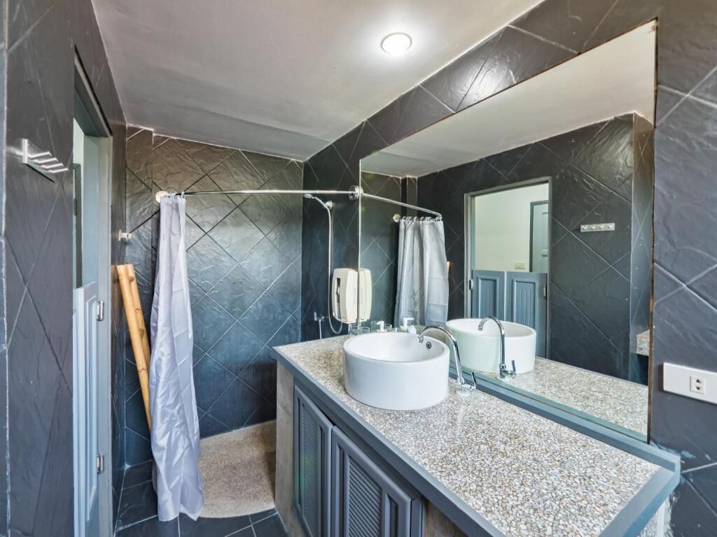 Un baño moderno con un espejo grande, dos lavamanos y una zona de ducha.