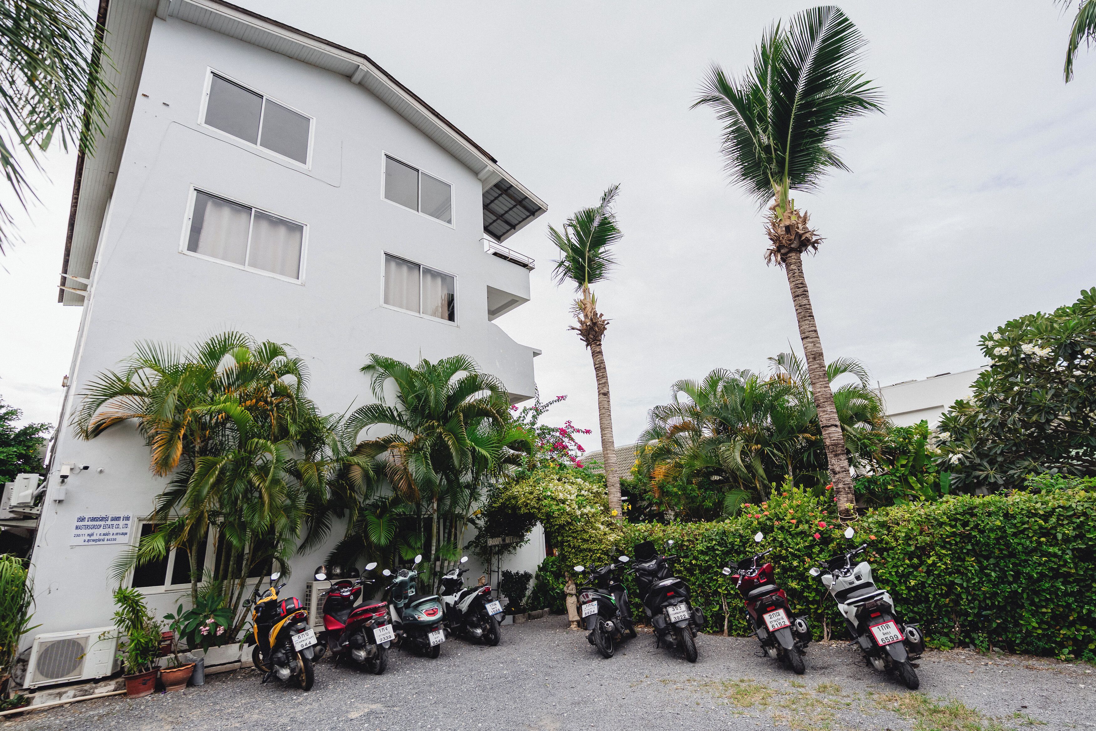 A white building with multiple windows and a parking area with motorcycles.