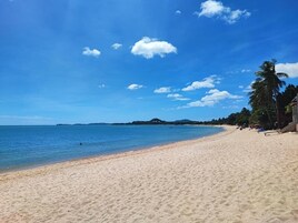 Una playa cerca, arena blanca, sombrillas, toallas de playa