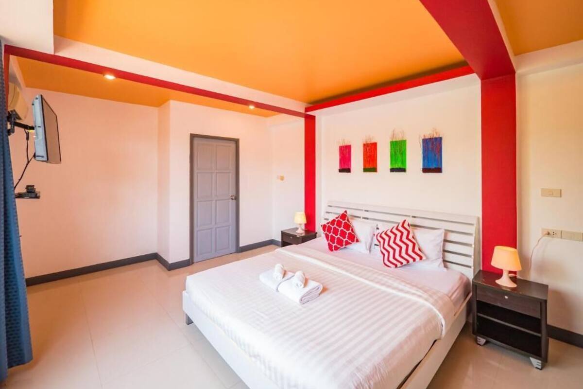 Una habitación de hotel con una cama grande, una mesita de noche con lámpara y una puerta.