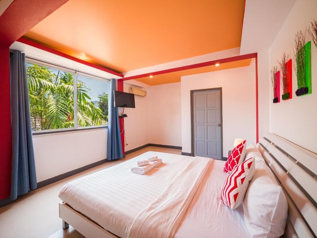 Una camera d'albergo con un letto, una finestra con tende, una porta e opere d'arte appese al muro.