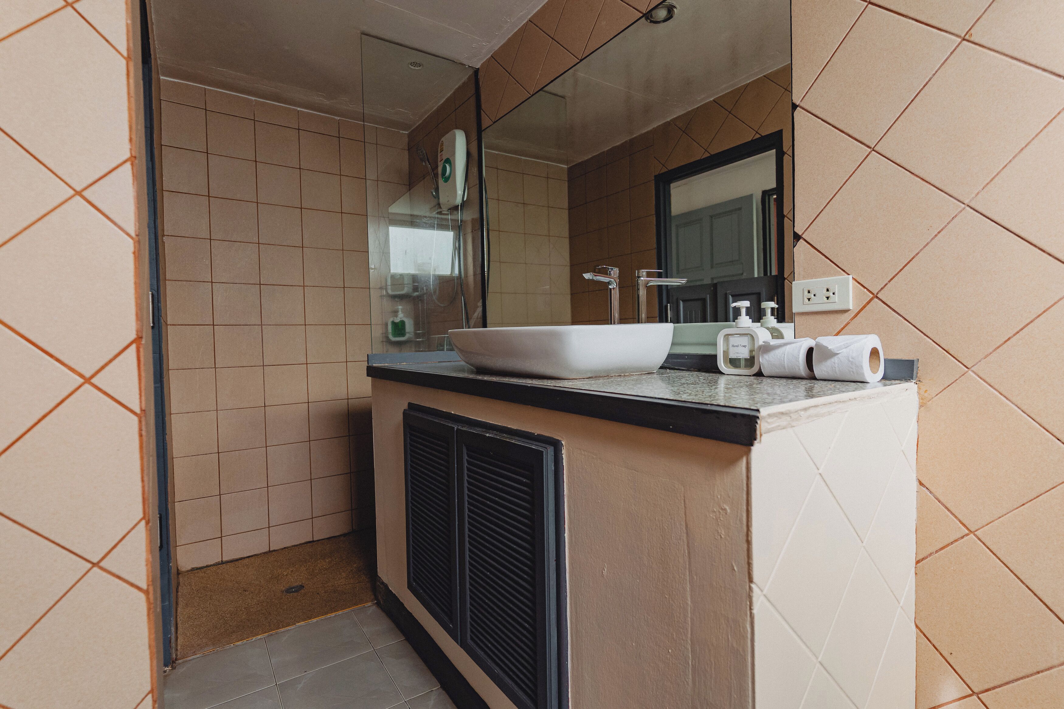 A modern bathroom with a large sink, mirror, and tiled walls.