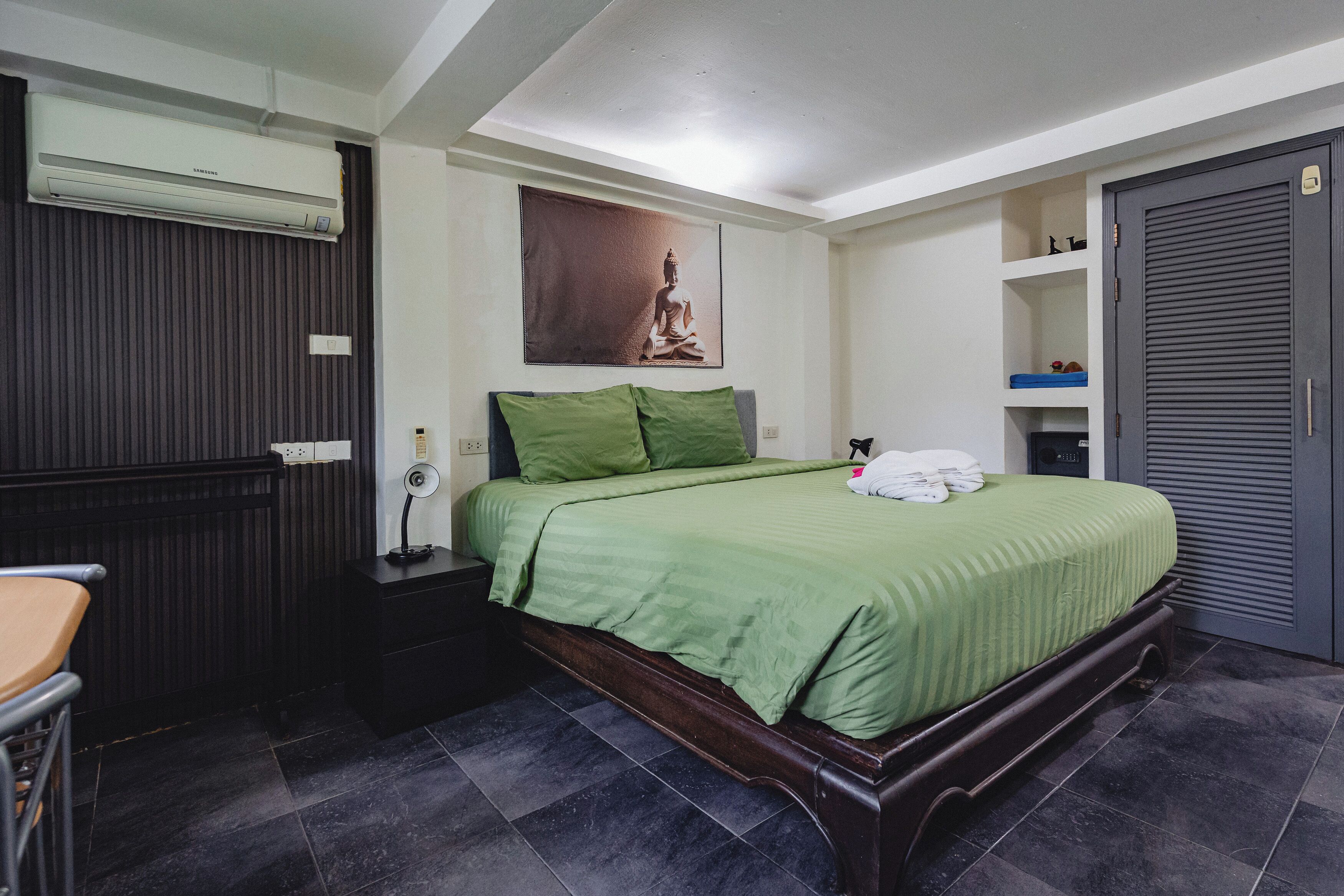 Un dormitorio con cama, mesita de noche y aire acondicionado instalado en la pared.