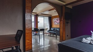A hotel room with a bed, a dining area with chairs and a table, a sofa, and a large window. - Lemon House apartment (Koh Samui)