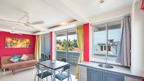A modern room with a dining area, a sofa, a ceiling fan, and large windows with curtains. - Lemon House apartment (Koh Samui)