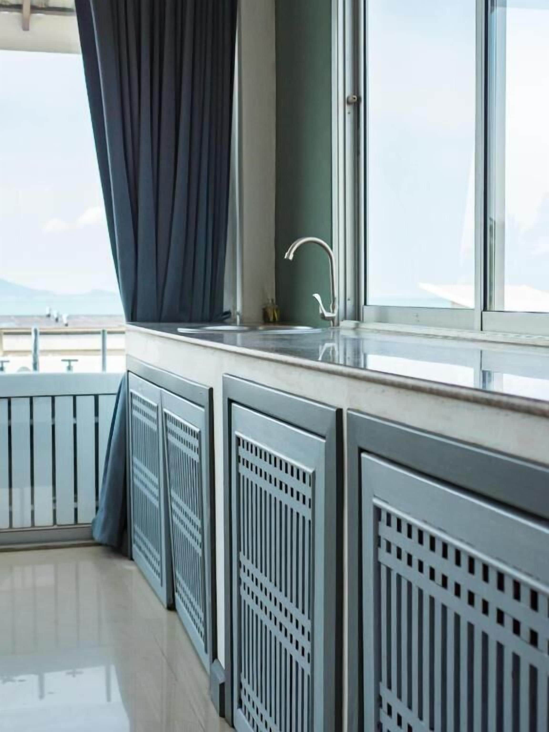 Ein Balkon mit Meerblick, ein Fenster mit Vorhang und ein Waschbecken.