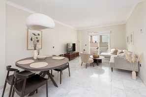 Relax in this stylish living space with a round dining table, sofa, and TV.