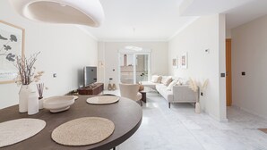 Ein modernes Wohnzimmer mit einem runden Esstisch, Sofas und einem Fernseher.