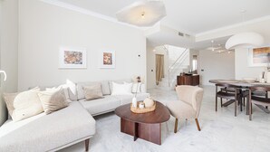 Ein modernes Wohnzimmer mit einem Ecksofa, einem runden Couchtisch und einem Essbereich mit Tisch und Stühlen.