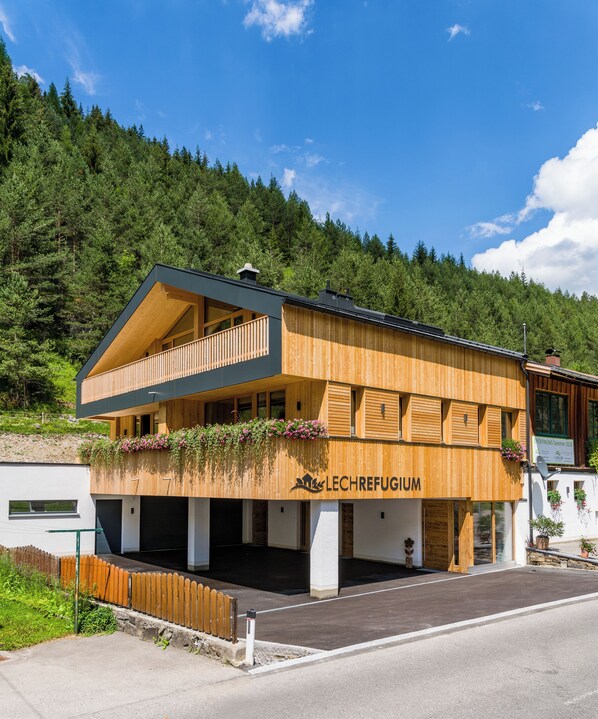 A two-story wooden building with a balcony, labeled "LECHREFUGIUM," surrounded by a forested hillside. - Erholungswelt Lechrefugium (Steeg)