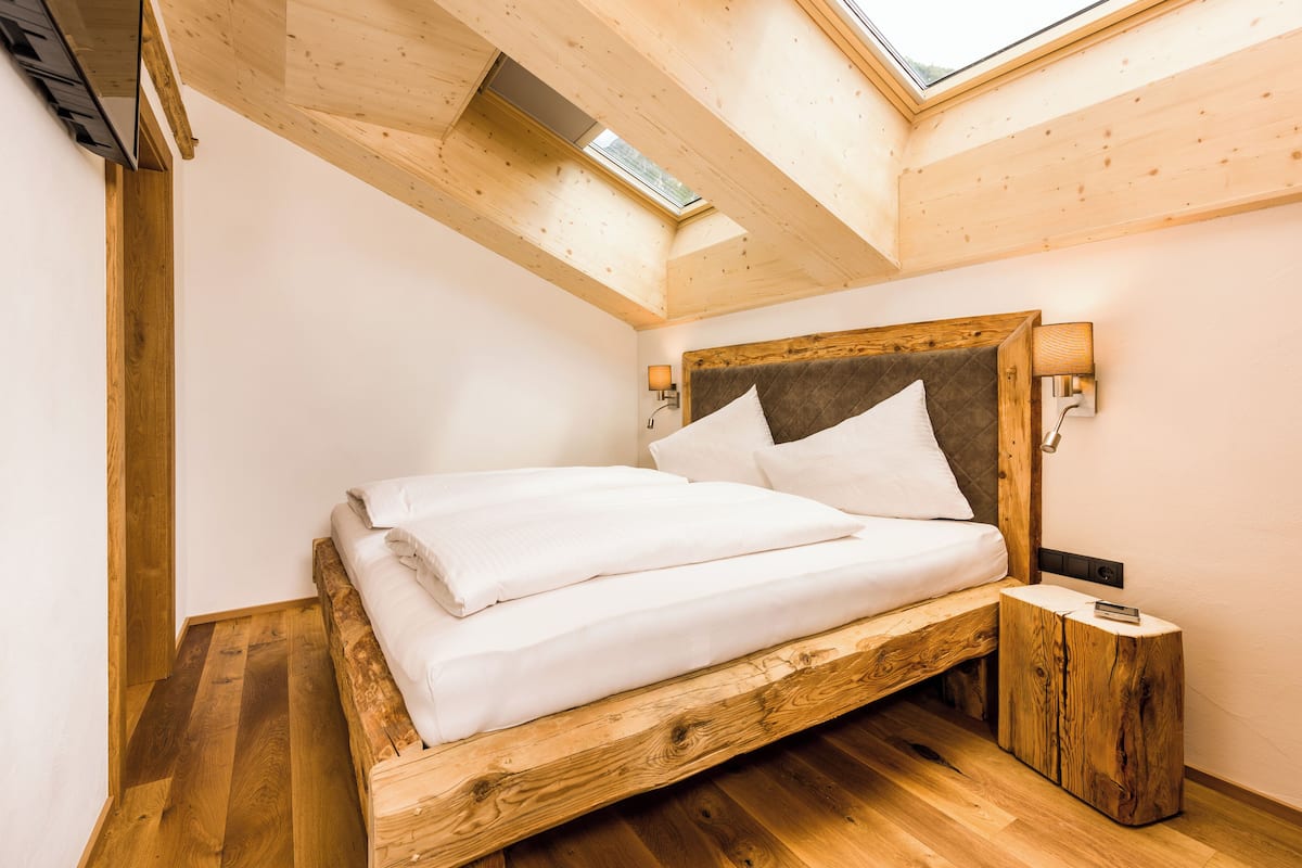 Une chambre à coucher avec un lit en bois, une lucarne et une table de chevet.