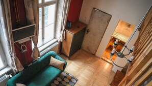 Un espace de vie compact avec un canapé vert, un tapis à motifs et un plancher en bois.