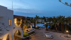 Un complexe hôtelier doté d’une piscine, de palmiers et offrant une vue sur la mer.