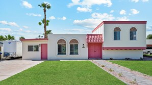 A two-story building with a red door and arched windows, a small attached garage, and a well-maintained lawn.
