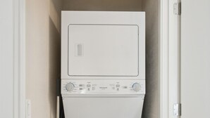 A laundry room with a front-loading washer and dryer stacked vertically.