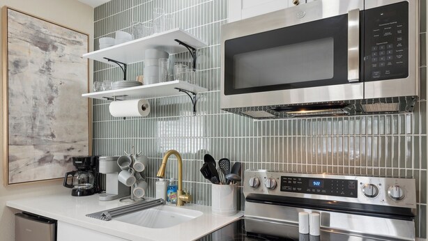 A modern kitchen with stainless steel appliances, a microwave, oven, and a coffee maker.
