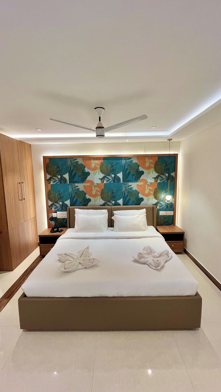 Una habitación de hotel moderna con una cama grande, un ventilador de techo y un colorido mural floral.