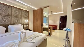 Une chambre d’hôtel avec un grand lit, une armoire en bois, un miroir et une télévision.