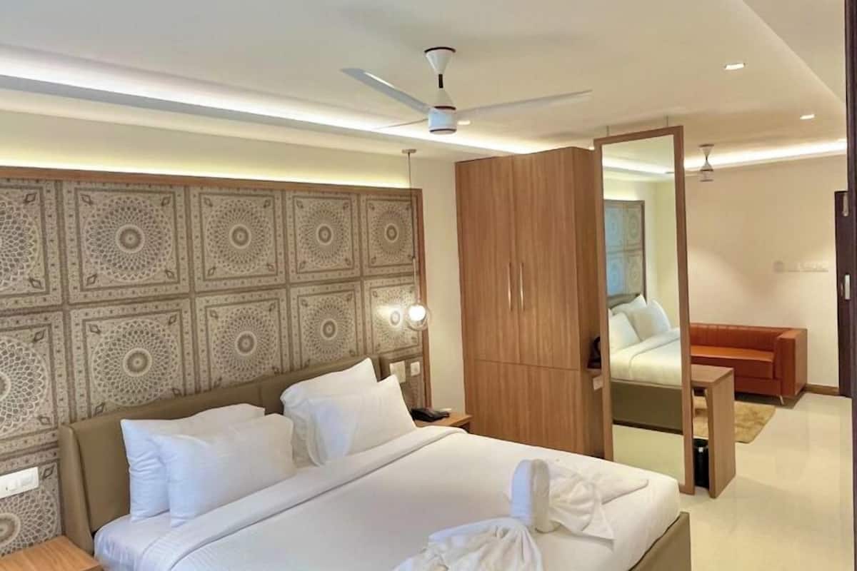 Een moderne hotelkamer met een groot bed, een plafondventilator en een houten garderobe.