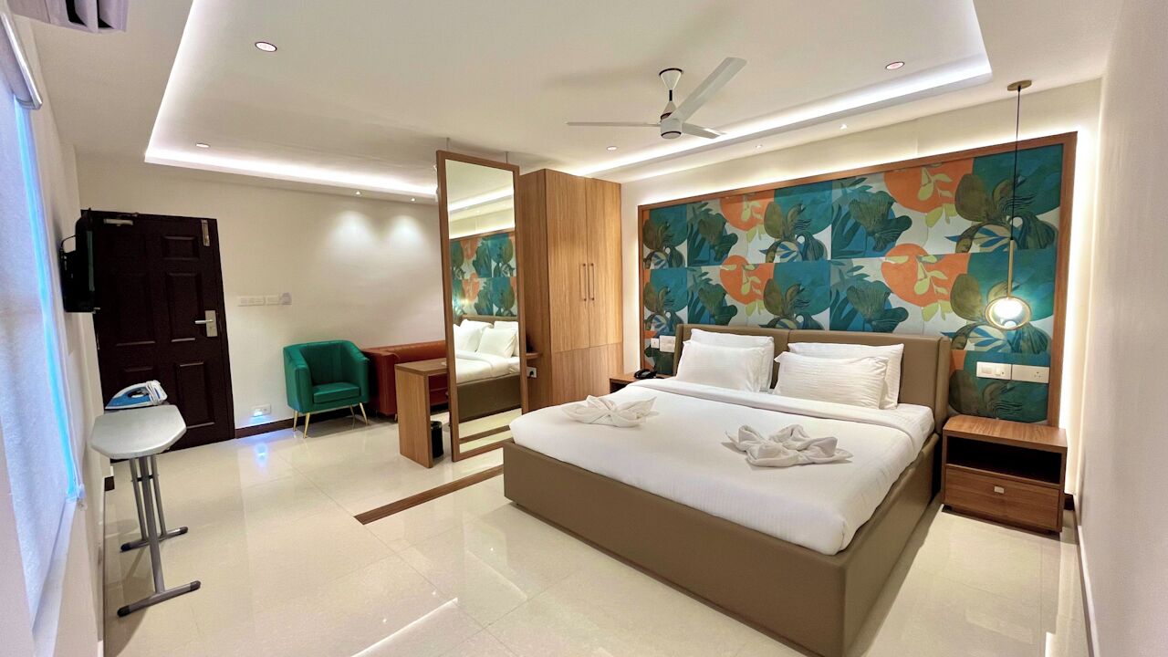 Una habitación de hotel moderna con una cama grande, una silla verde, un escritorio y una pared con un mural floral.