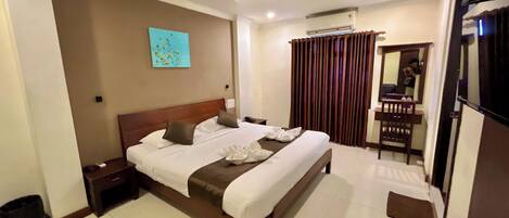 Quarto de hotel com uma cama grande, mesa de cabeceira, espelho, cortina e ventilador de teto.
