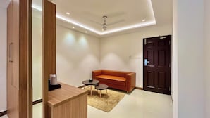 A modern room with a wooden desk, a leather sofa, and a small round table. - Hotel Pearl Palace (Kanayannur)