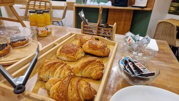 Un plateau de petit-déjeuner avec des croissants et des bouteilles de jus sur une table en bois, dans un café.