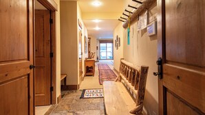 A hallway with wooden doors, a bench, a patterned rug, and a bench rail.
