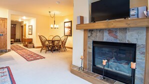 A living room with a fireplace, a television, and a dining area with a table and chairs.