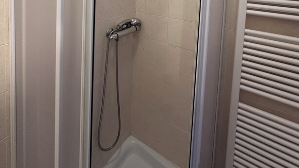 A glass-enclosed shower with a handheld showerhead and a wall-mounted control panel. - Aselli Palace Historic Center of Cremona (Cremona)
