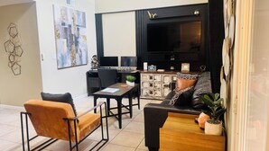 Ein modernes Wohnzimmer mit einem schwarzen Sofa, einem Holztisch und einer schwarzen TV-Konsole.